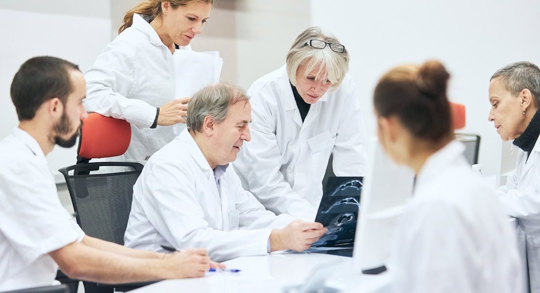 Six doctors discussing an X-Ray result at a meeting